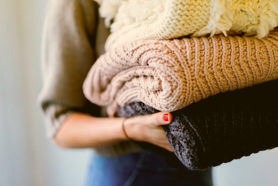 Someone carrying a stack of folded knitwear
